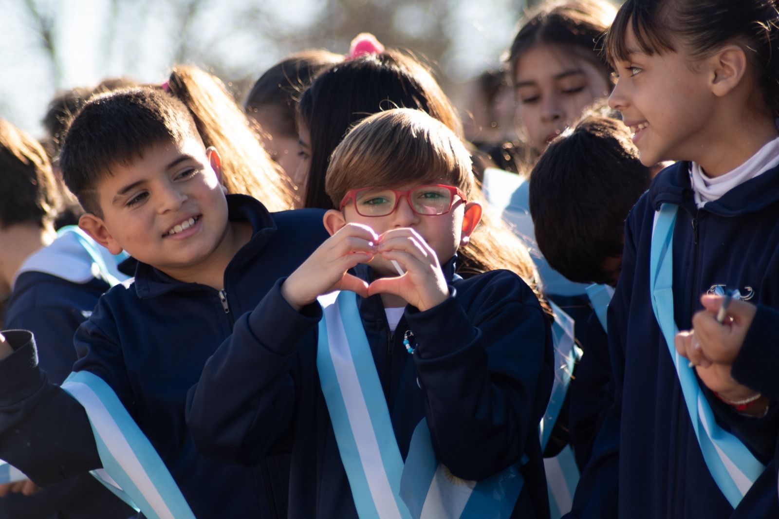 Una niña hace un corazón con las manos durante el acto por el Día de la Bandera en Roldán