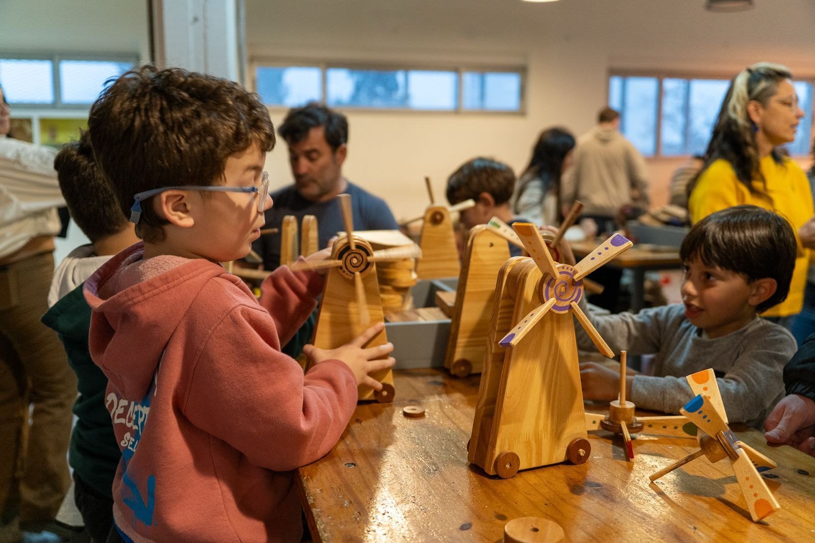 Dos chicos hacen girar molinos de madera pintados que construyeron en un taller de construcción